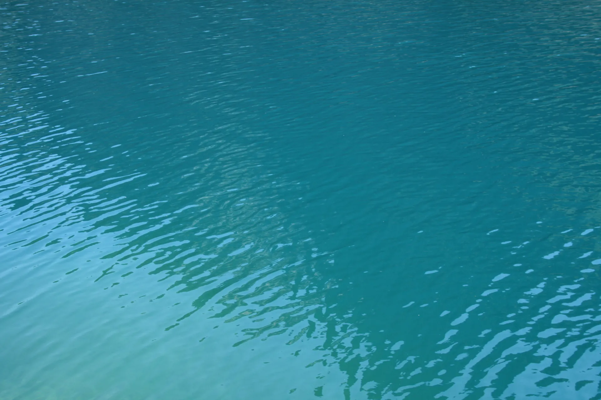 Surface d’une étendue d’eau turquoise ridée par le vent.