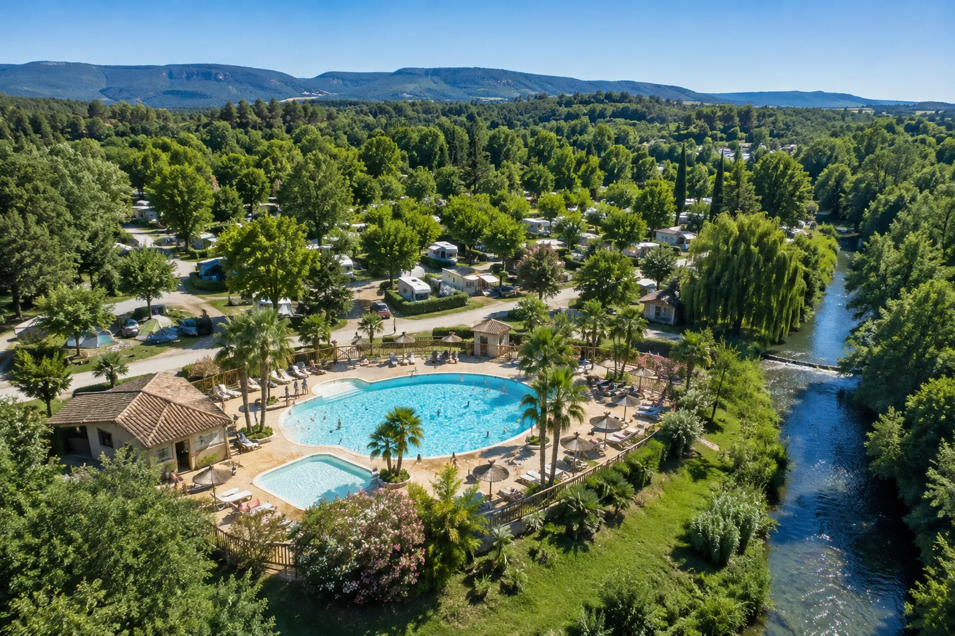 Camping arboré en bord de rivière, vu du ciel, avec son espace aquatique.